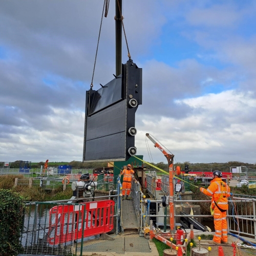 Large flood gate being lifted into position on construction site