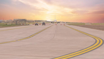 Looking down a runway, with a plan in the distance at sunset