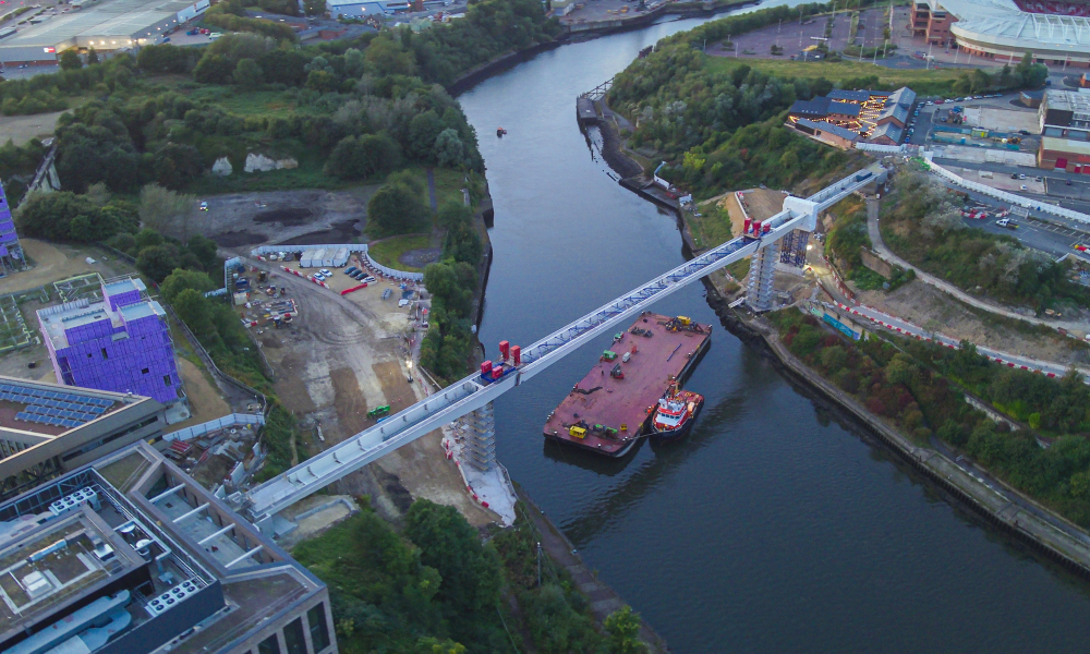 A barge on a river going under a bridge. 