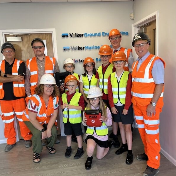 Children in high vis receiving a defibrillator.